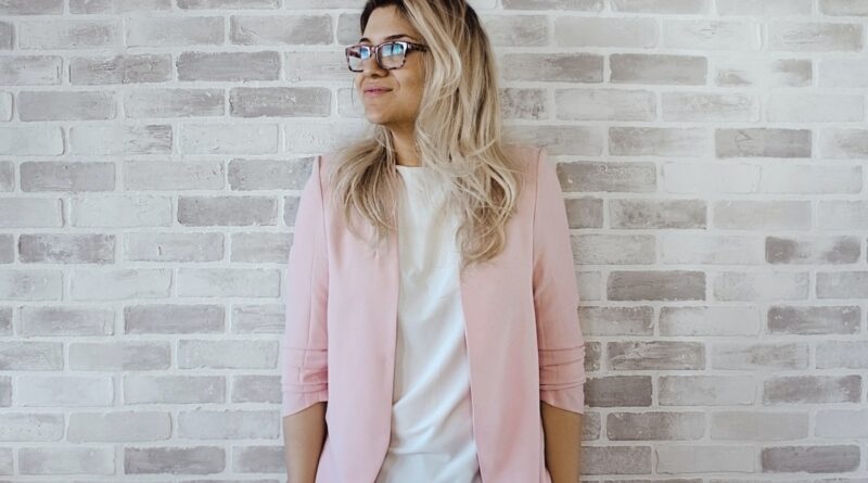 Woman in Pink Cardigan and White Shirt Leaning on the Wall