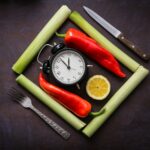 a clock surrounded by vegetables and a knife